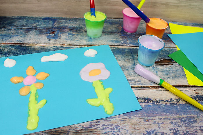 A photo of a picture of flowers and clouds made with puffy paint.