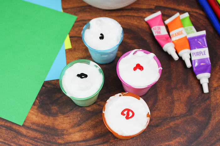 Adding four different colors of food coloring the each container of puffy paint