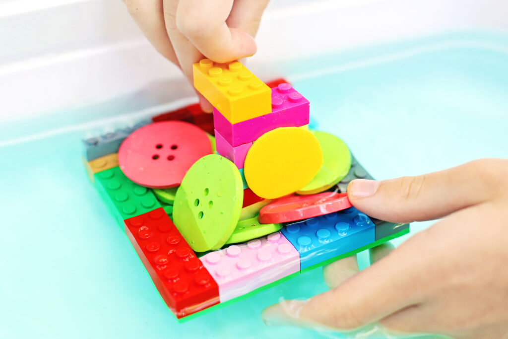 Testing Boat with Buttons - Cultivating Brilliant Minds building the boat higher with legos