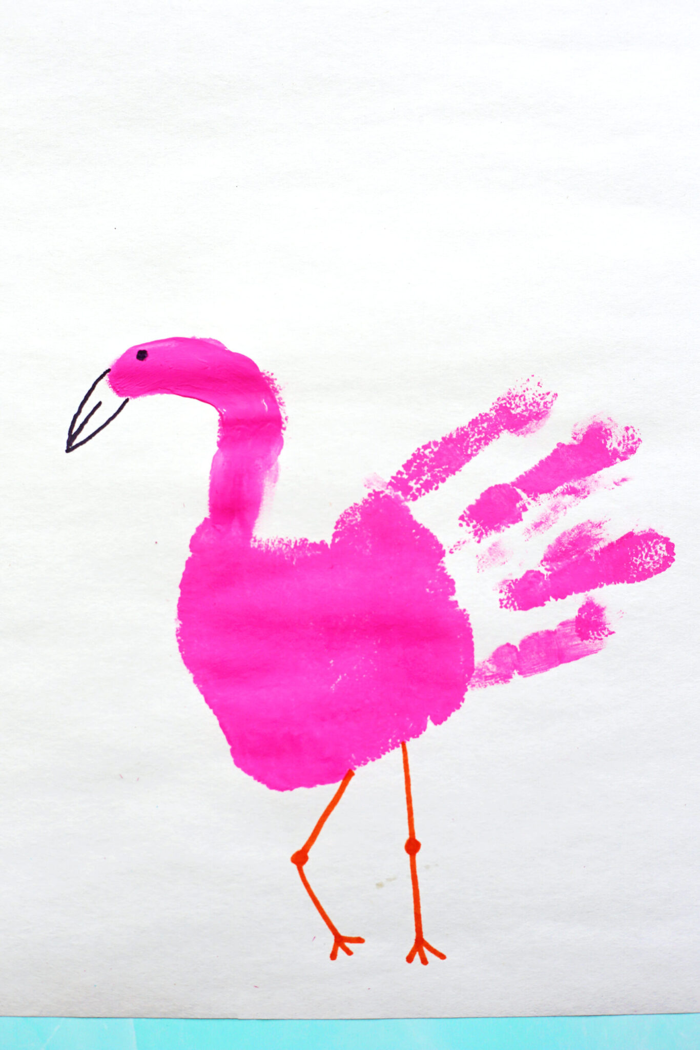 Pink handprint flamingo craft for kids with a painted handprint body and long legs