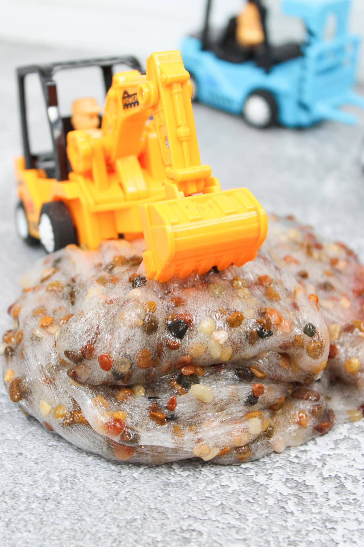 Pebble Slime Recipe - Cultivating Brilliant Minds slime made with pebbles in it with a construction backhoe on top