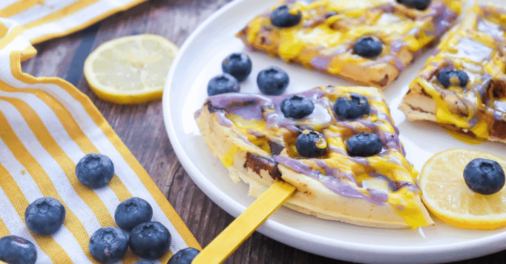 blueberry lemon waffle pops on a stick with melted purple and yellow chocolate and blueberries