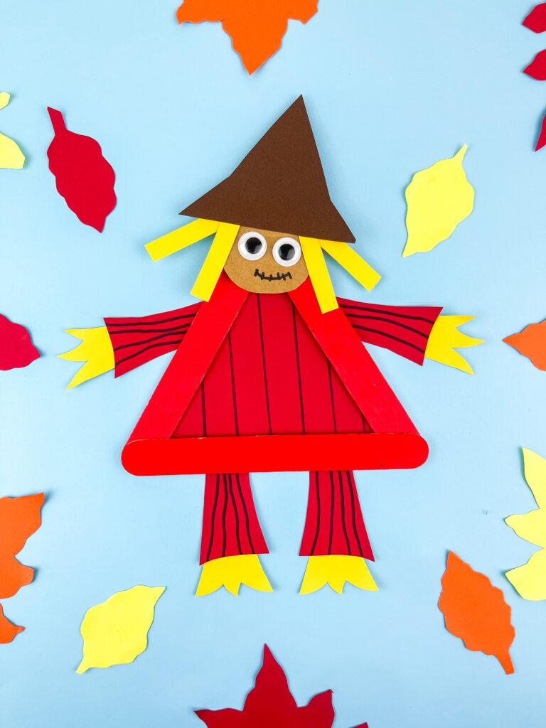 Photo 7-15-25 9 58 21 PM - Cultivating Brilliant Minds scarecrow popsicle craft on blue paper surrounded by construction paper leaves