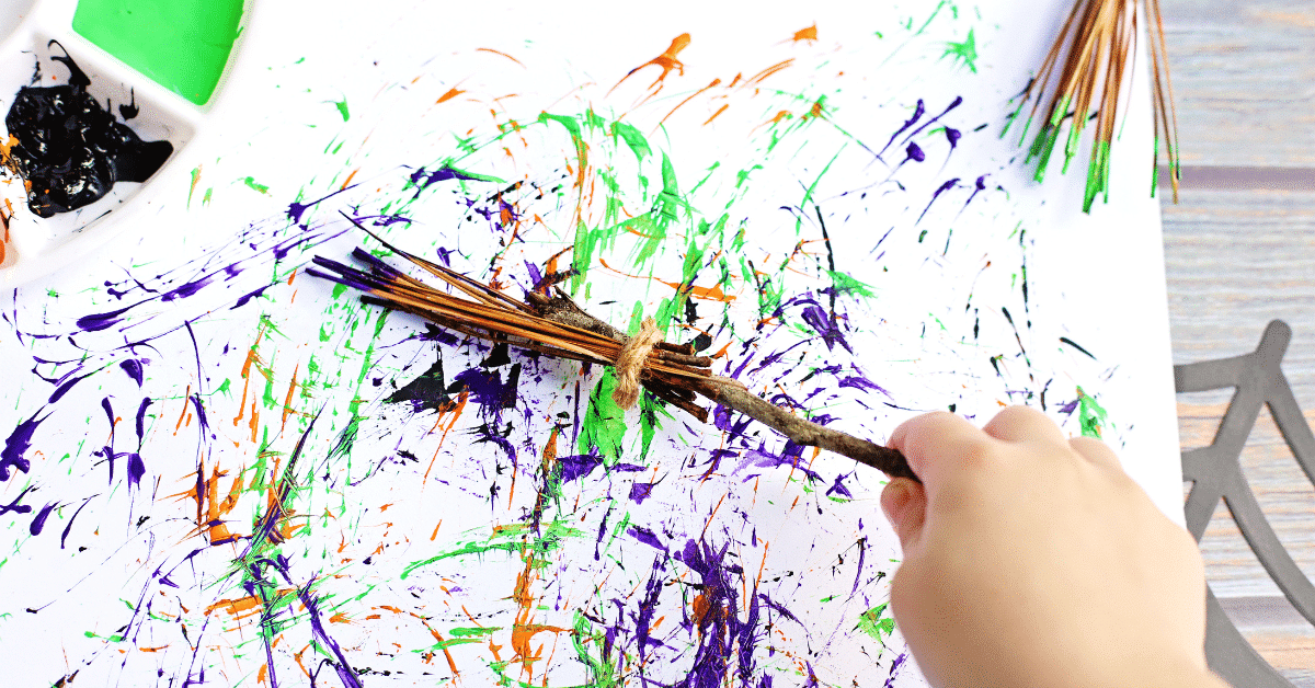 a diy paintbrush made out of sticks with a kid using it to paint a canvas