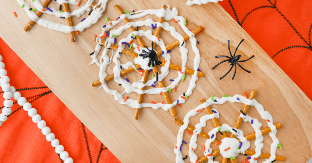 pretzels with icing and halloween sprinkles to look like a spider web