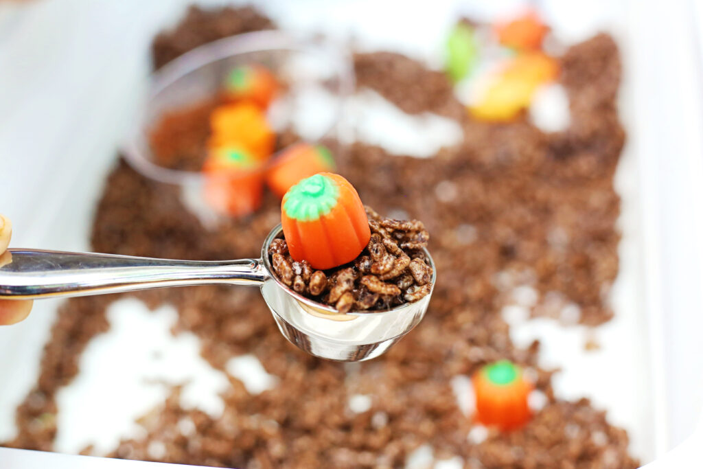 Edible Pumpkin Patch Sensory Bin 8 - Cultivating Brilliant Minds Rice krispies and a pumpkin from the sensory bin scooped up in a small measuring spoon