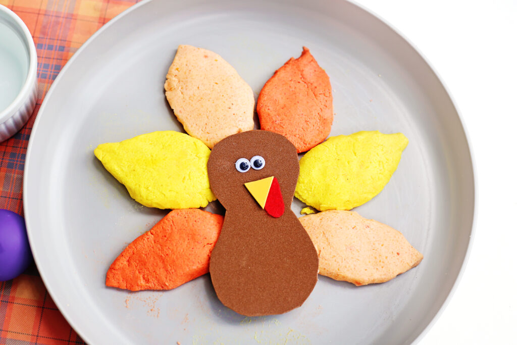 Place turkey body on feathers - Cultivating Brilliant Minds turkey with baking soda feathers on a paper plate