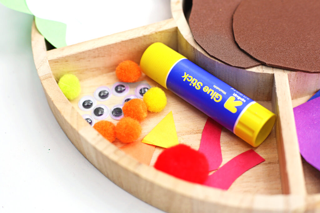 Turkey in Disguise Craft 2 - Cultivating Brilliant Minds a close up of a glue stick, pom poms, and googly eyes