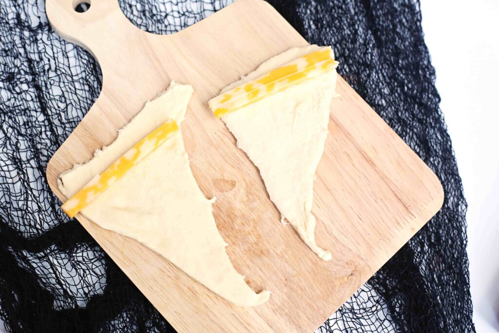 Witch Hat Pizza Snacks For Halloween - Cultivating Brilliant Minds dough cut into a triangle with cheese on it