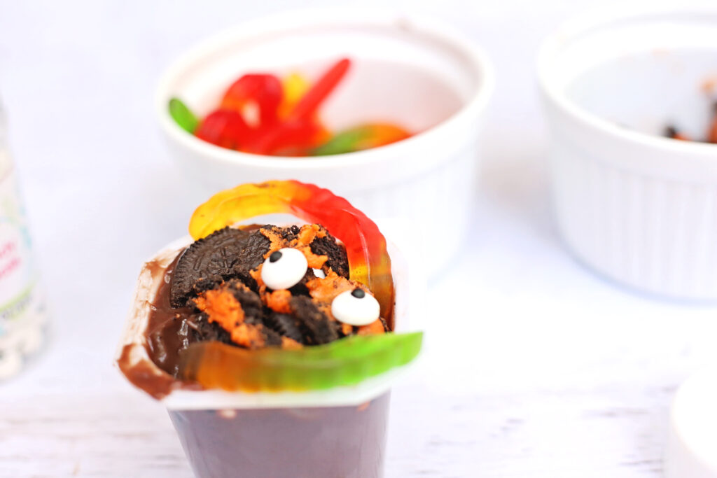 Witchs Brew Pudding Cups - Cultivating Brilliant Minds Pudding cup with eye balls, crushed oreos, and gummy worms