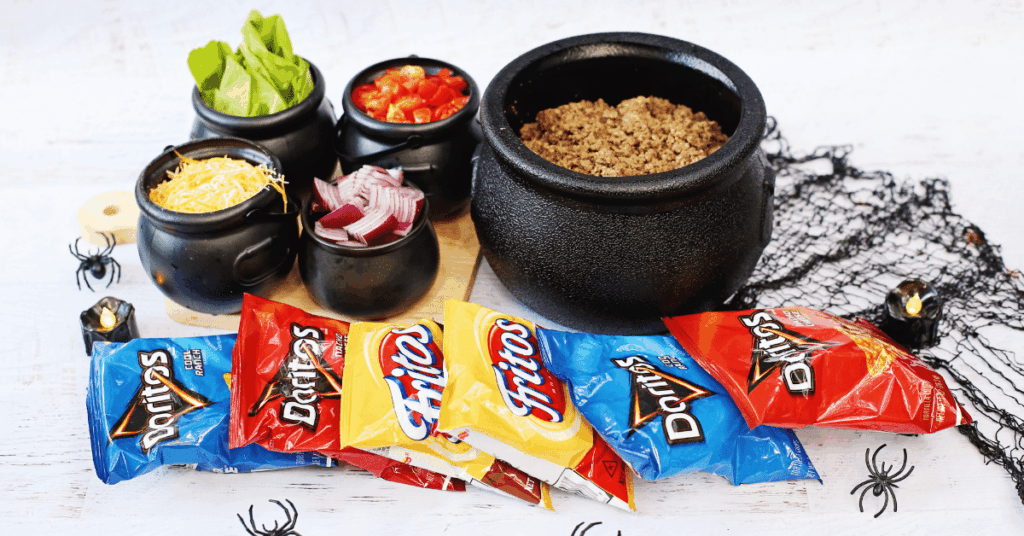 a walking taco bar with bags of chips. each taco ingredient is in a cauldron