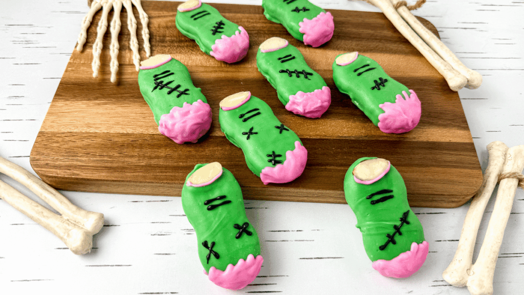 nutter butters covered in green chocolate and decorated to look like zombie fingers