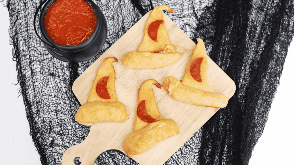 pizza in the shape of a witch hat with a crescent moon shaped piece of pepperoni on it