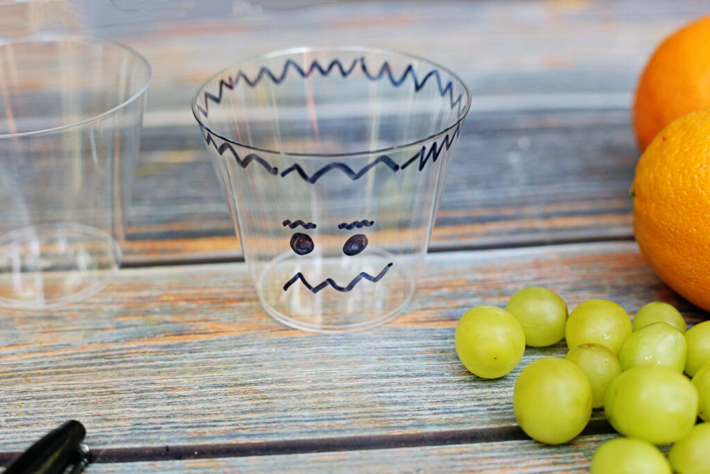 Healthy Halloween Snacks - Cultivating Brilliant Minds frankenstein face drawn on a plastic cup