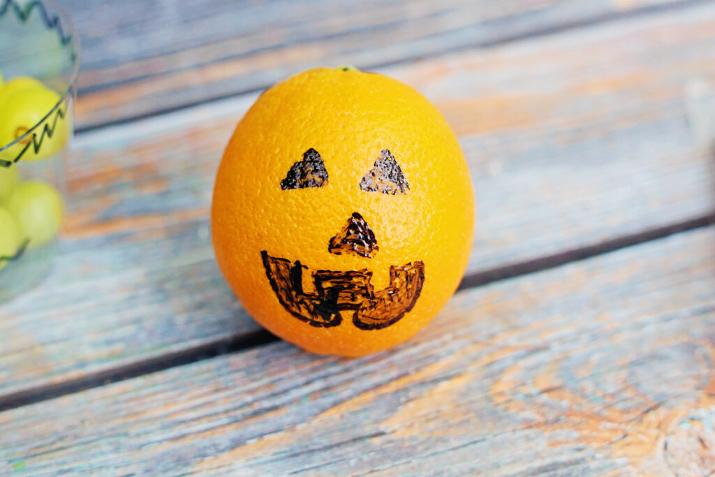 Healthy Halloween Snacks - Cultivating Brilliant Minds orange with jack o lantern face drawn on