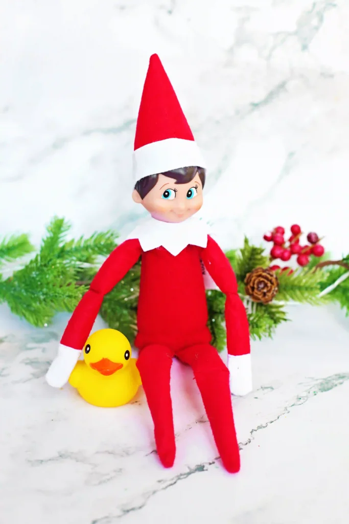 Elf on the Shelf Idea - Cultivating Brilliant Minds an elf on the shelf next to a duck with a sign that reads "I ducked the halls! Can you find all 10 ducks?"