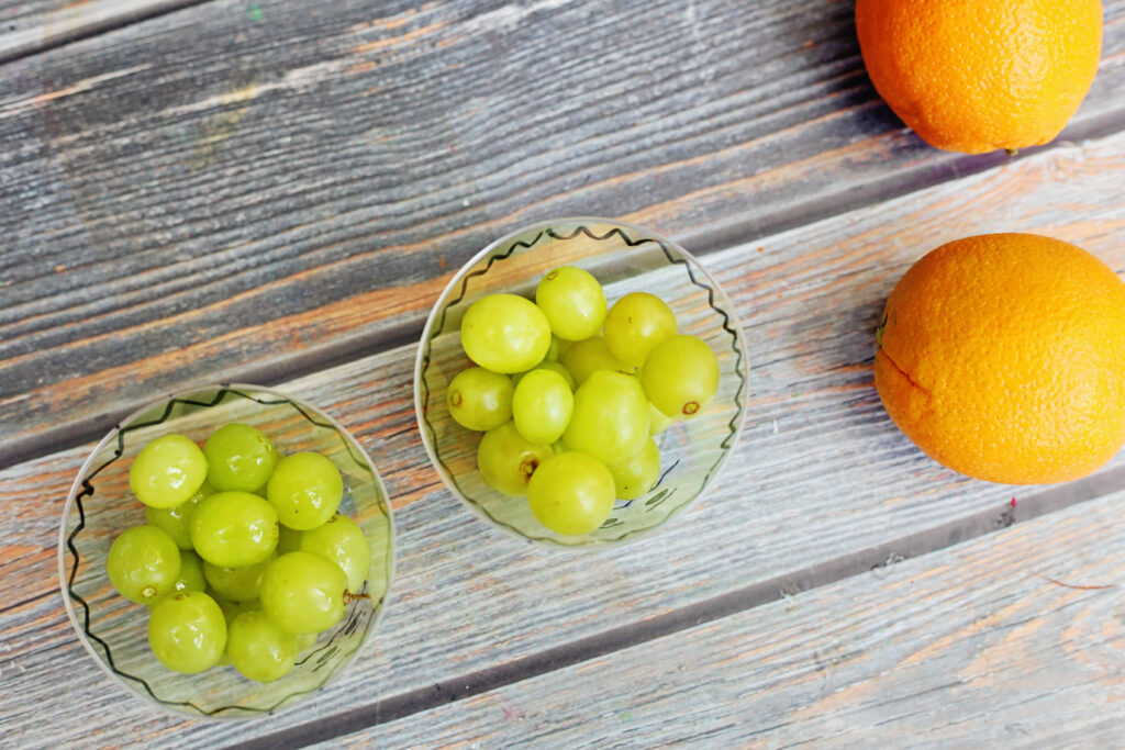Healthy Halloween Snacks - Cultivating Brilliant Minds cup with grapes in it and oranges