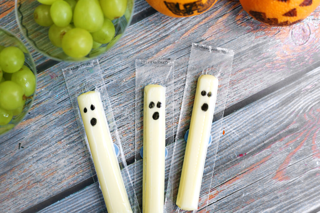 Healthy Halloween Snacks - Cultivating Brilliant Minds string cheese with ghost faces drawn on