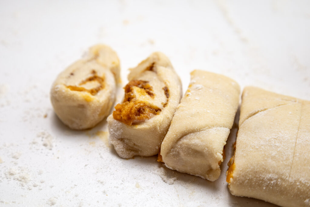 Pumpkin Cinnamon Rolls - Cultivating Brilliant Minds rolled dough cut into slices