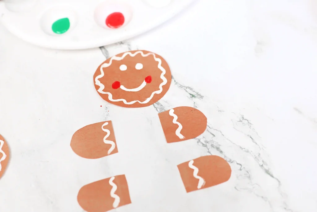 Pieces of a gingerbread cut out of construction paper painted to look like a gingerbread man
