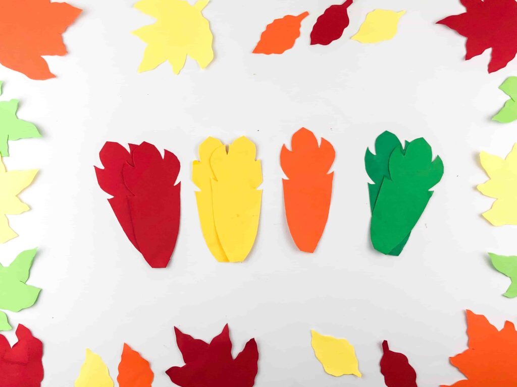 Thanksgiving Turkey Popsicle Stick Craft - Cultivating Brilliant Minds feathers cut out of construction paper