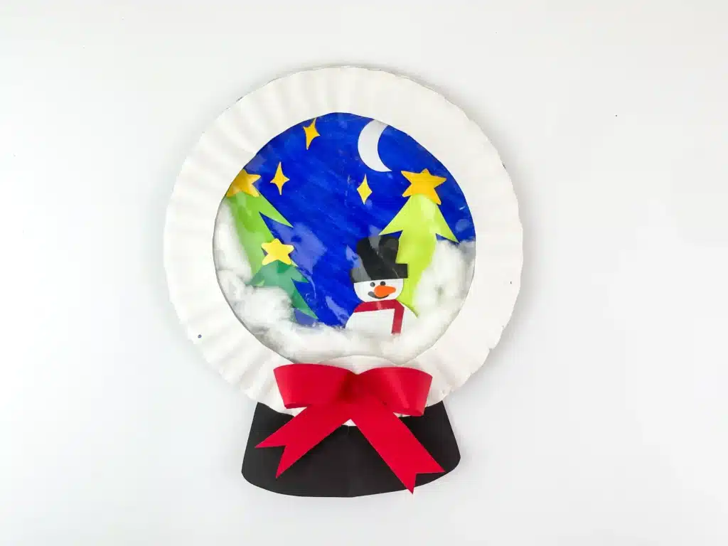 Snowglobe Paper Plate Craft - Cultivating Brilliant Minds a paper plate craft that looks like a snowglobe with a snowman and trees inside