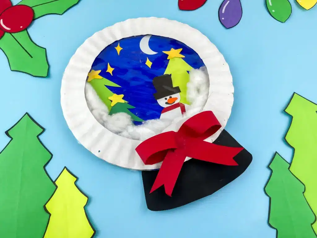 Snowglobe Paper Plate Craft - Cultivating Brilliant Minds a paper plate craft that looks like a snowglobe with a snowman and trees inside