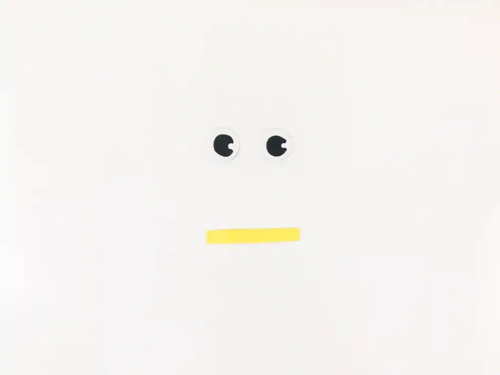 Snowman Popsicle Stick Ornament - Cultivating Brilliant Minds eyes cut out of construction paper and a yellow rectangle