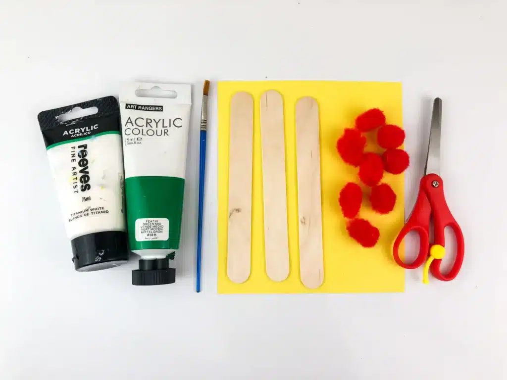 Christmas Tree Popsicle Stick Ornament - Cultivating Brilliant Minds supplies to make the christmas tree popsicle stick ornament : green and white paint, popsicle sticks, red pom poms, yellow construction paper, and scissors