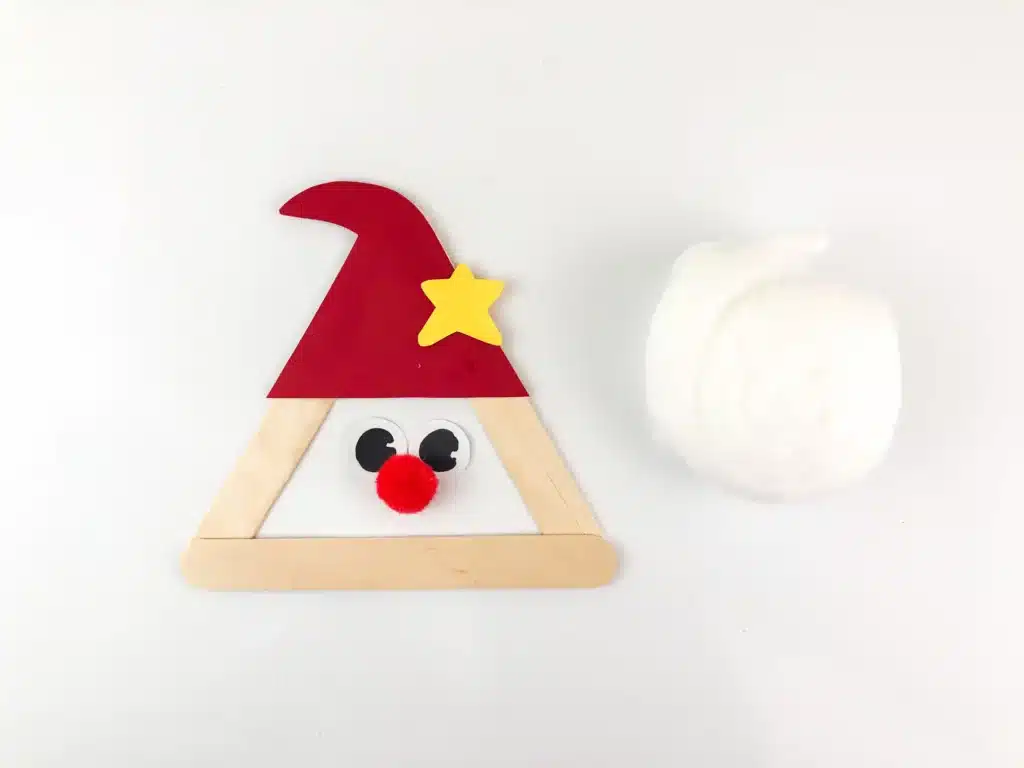 Santa Popsicle Stick Craft - Cultivating Brilliant Minds popsicle sticks glued into a triangle with a red hat, red nose next to cotton