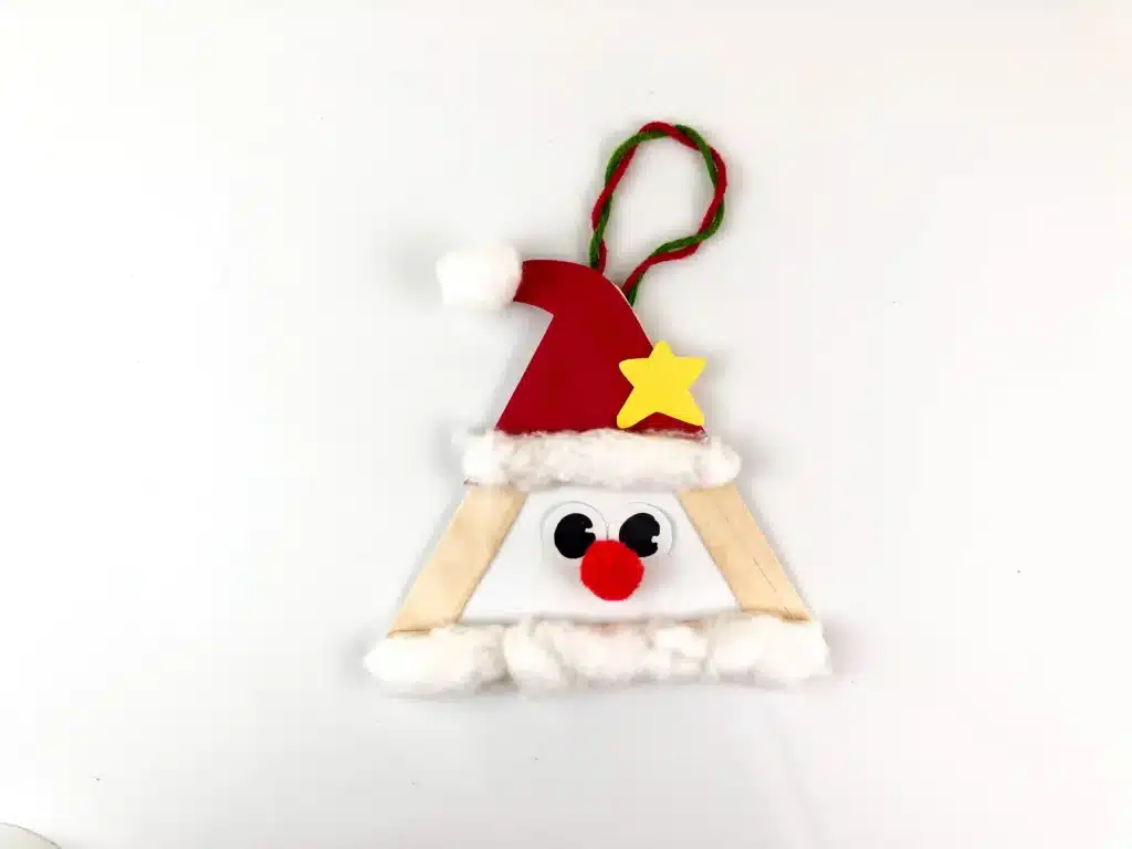 Santa Popsicle Stick Craft - Cultivating Brilliant Minds popsicle sticks glued into a triangle with a red hat, red nose, and cotton ball beard to look like santa