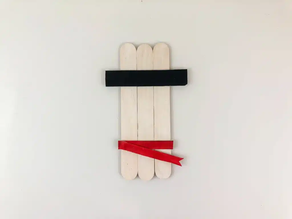 Snowman Popsicle Stick Ornament - Cultivating Brilliant Minds three popsicle sticks painted white with red ribbon for a scarf and a black hat brim