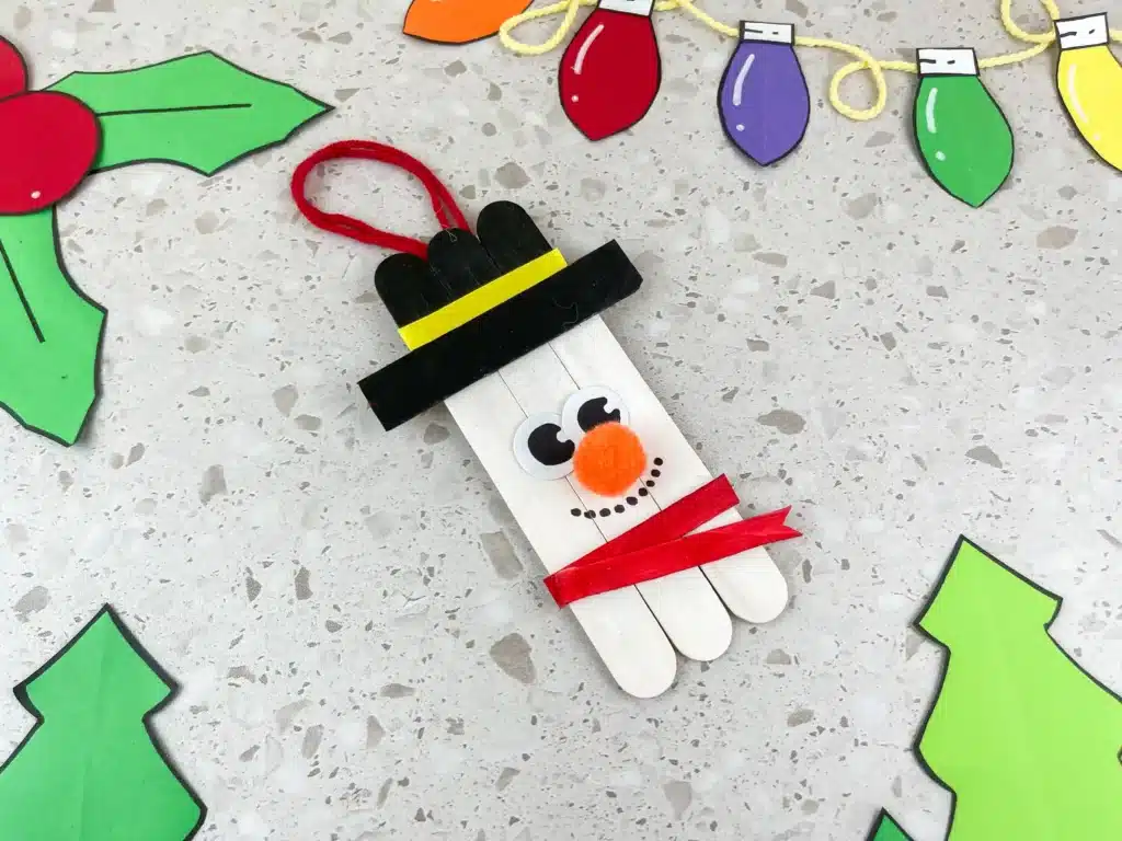 Snowman Popsicle Stick Ornament - Cultivating Brilliant Minds popsicle sticks glued together and decorated to look like a snowman to make a snowman popsicle stick ornament for the tree