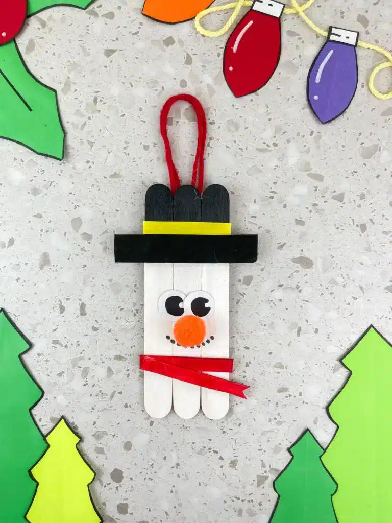 popsicle sticks glued together and decorated to look like a snowman to make a snowman popsicle stick ornament for the tree