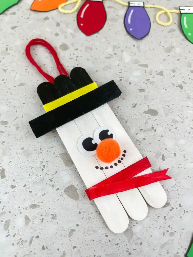 Snowman Popsicle Stick Ornament - Cultivating Brilliant Minds popsicle sticks glued together and decorated to look like a snowman to make a snowman popsicle stick ornament for the tree