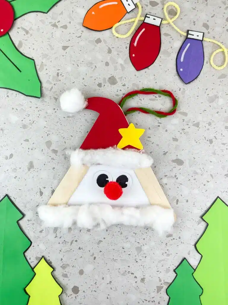 Santa Popsicle Stick Craft - Cultivating Brilliant Minds popsicle sticks glued into a triangle with a red hat, red nose, and cotton ball beard to look like santa