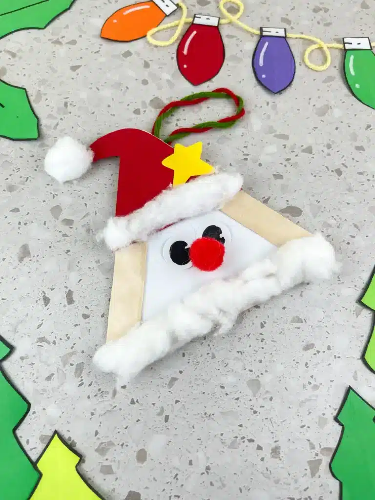 Santa Popsicle Stick Craft - Cultivating Brilliant Minds popsicle sticks glued into a triangle with a red hat, red nose, and cotton ball beard to look like santa