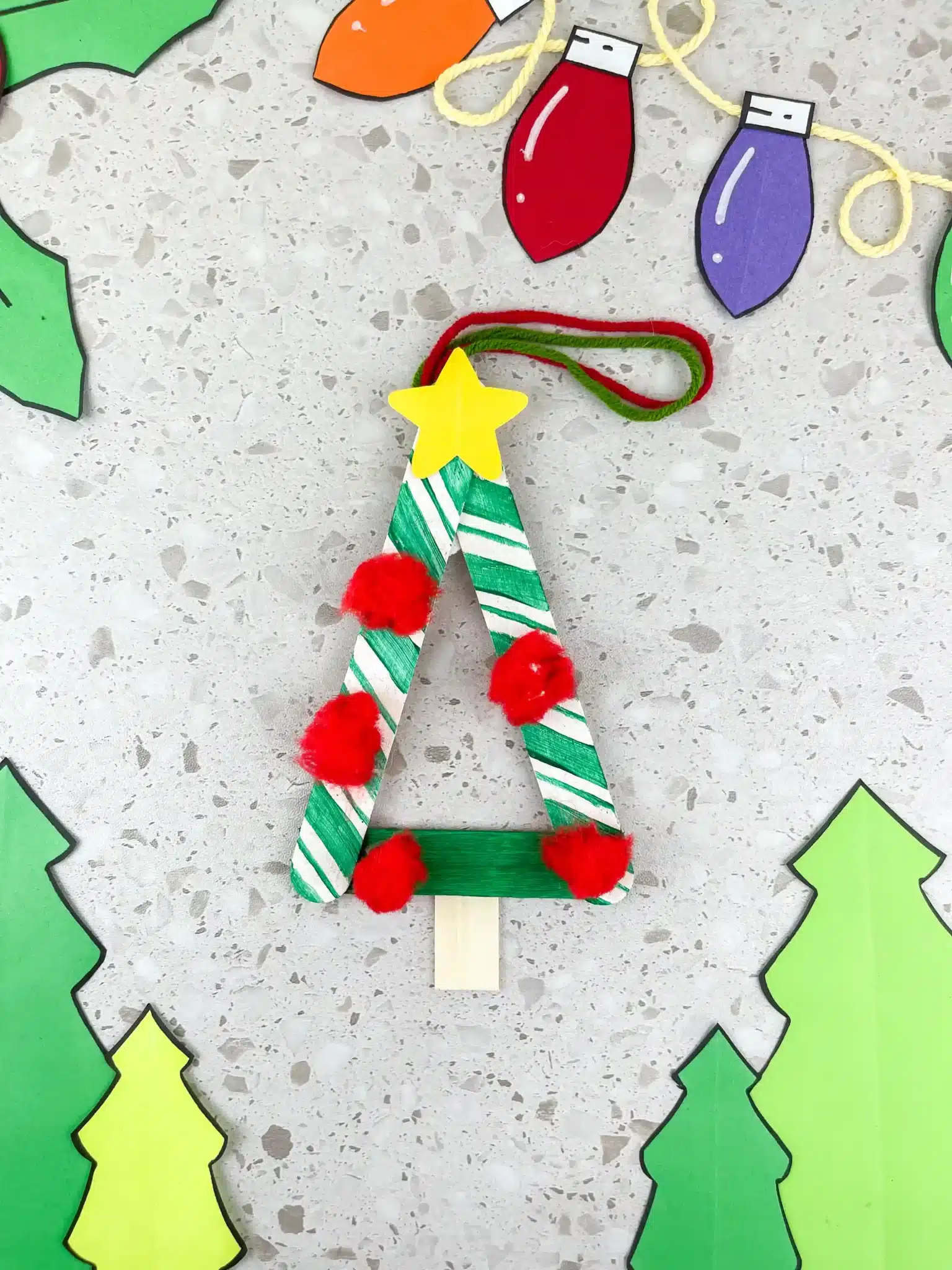 a popsicle stick christmas ornament decorated to look like a tree