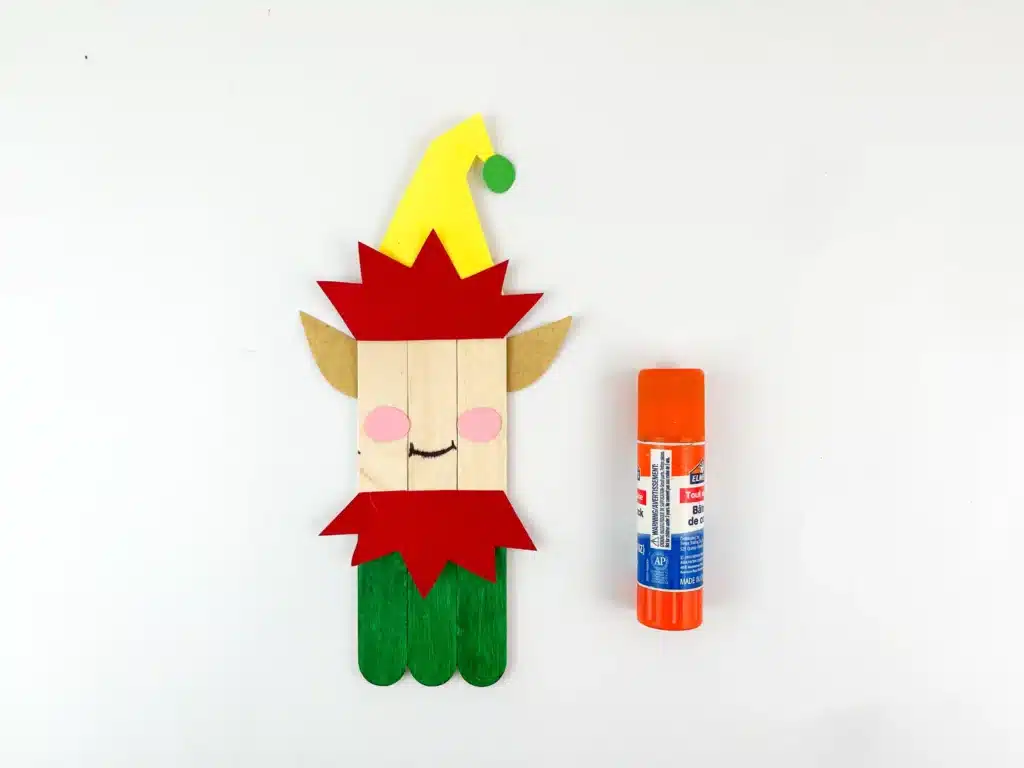 three popsicle sticks glued together with the bottom painted green, a mouth and rosy cheeks, with elf ears and an elf hat