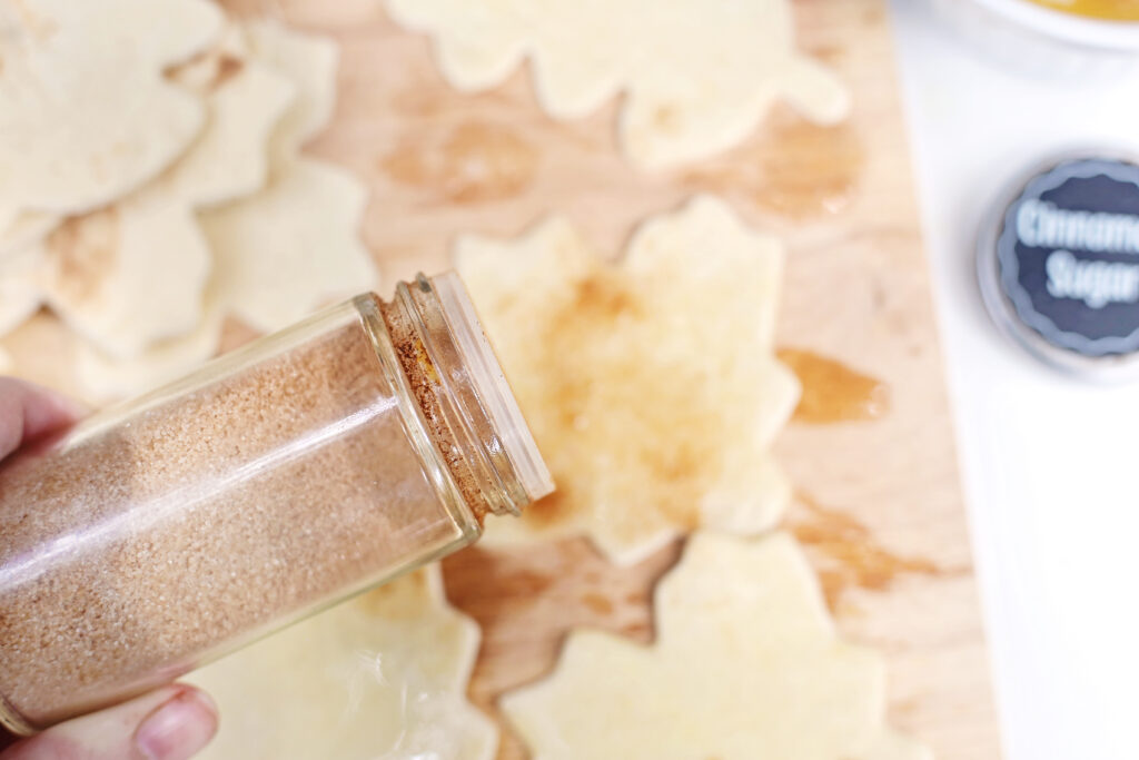 Cinnamon Sugar Tortilla Chips - Cultivating Brilliant Minds sprinkling cinnamon on the tortillas