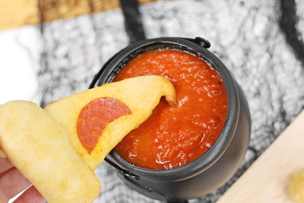 Witch Hat Pizza Snacks For Halloween - Cultivating Brilliant Minds pizza shaped like witch hat being dipped into marinara sauce
