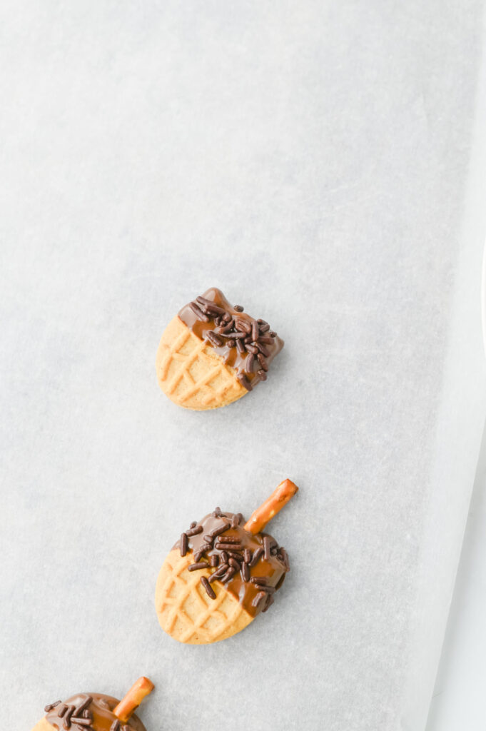 Nutter Butter Acorns - Cultivating Brilliant Minds adding chocolate sprinkles while the melted chocolate is still wet