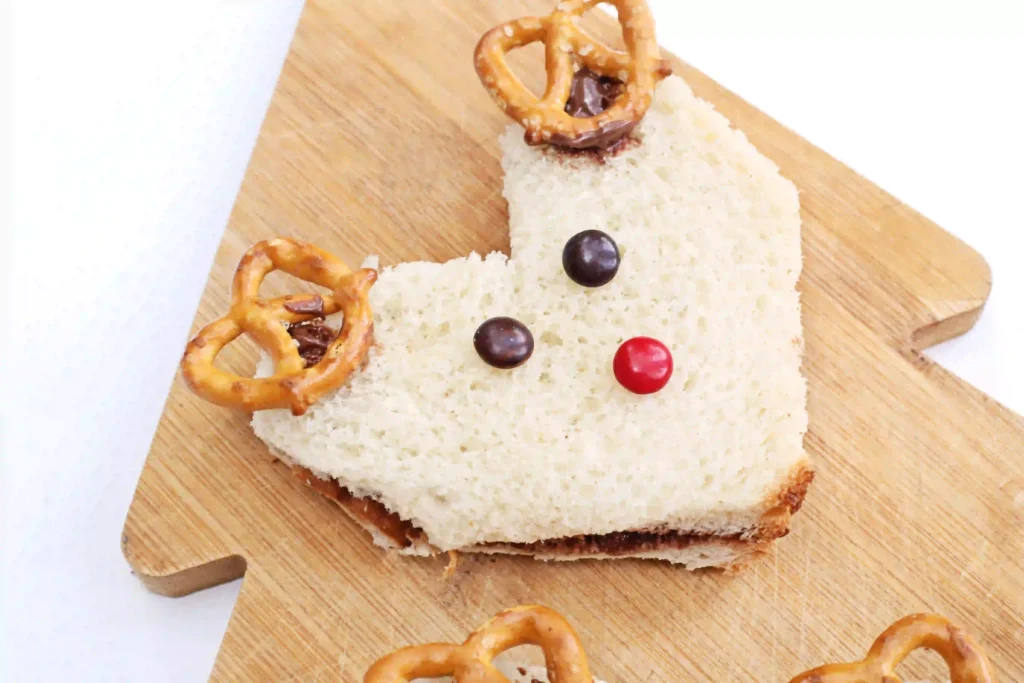 Nutella Reindeer Sandwiches - Cultivating Brilliant Minds a nutella sandwich decorated with m&ms and pretzels to look like a reindeer