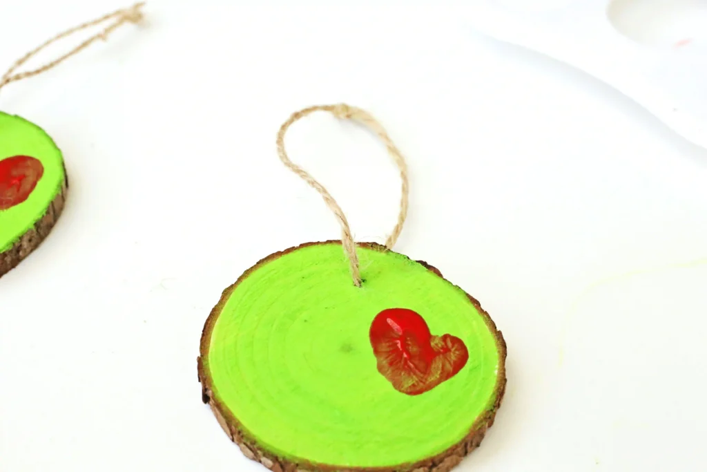 Grinch Heart Wood Slice Ornament Craft - Cultivating Brilliant Minds a wood slice ornament decorated to look like the grinch's heart