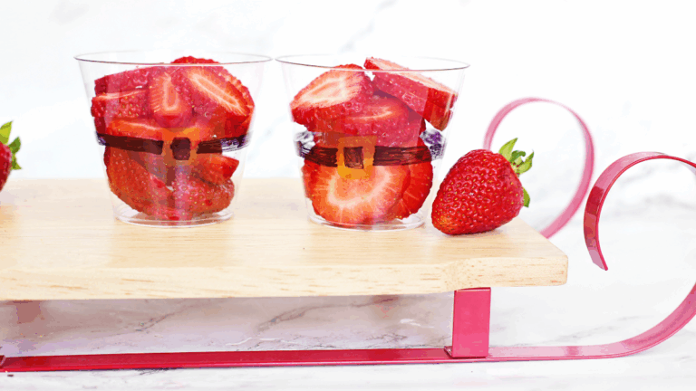 Sliced strawberries in a cup decorated to look like santa's suit