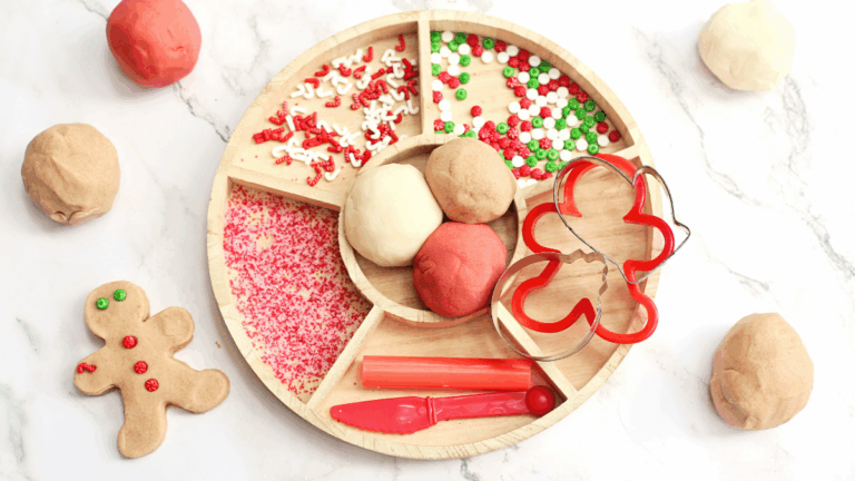 a playdough tray filled with holiday-related items like red and green sprinkles and gingerbread cookie cutters