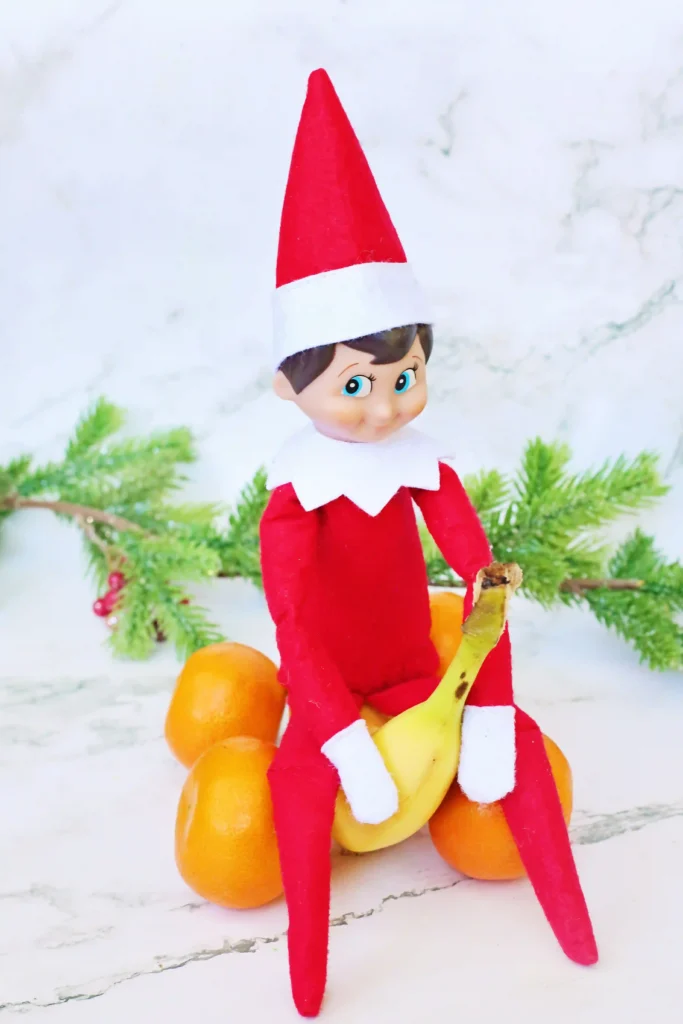 Elf on the Shelf Idea: Banana Races - Cultivating Brilliant Minds an elf on the shelf on a banana made to look like a car with oranges for wheels