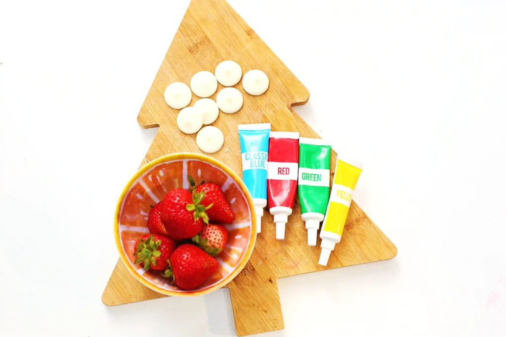Christmas Light Strawberries - Cultivating Brilliant Minds strawberries, vanilla candy melts and food coloring on a wooden board that is shaped like a tree