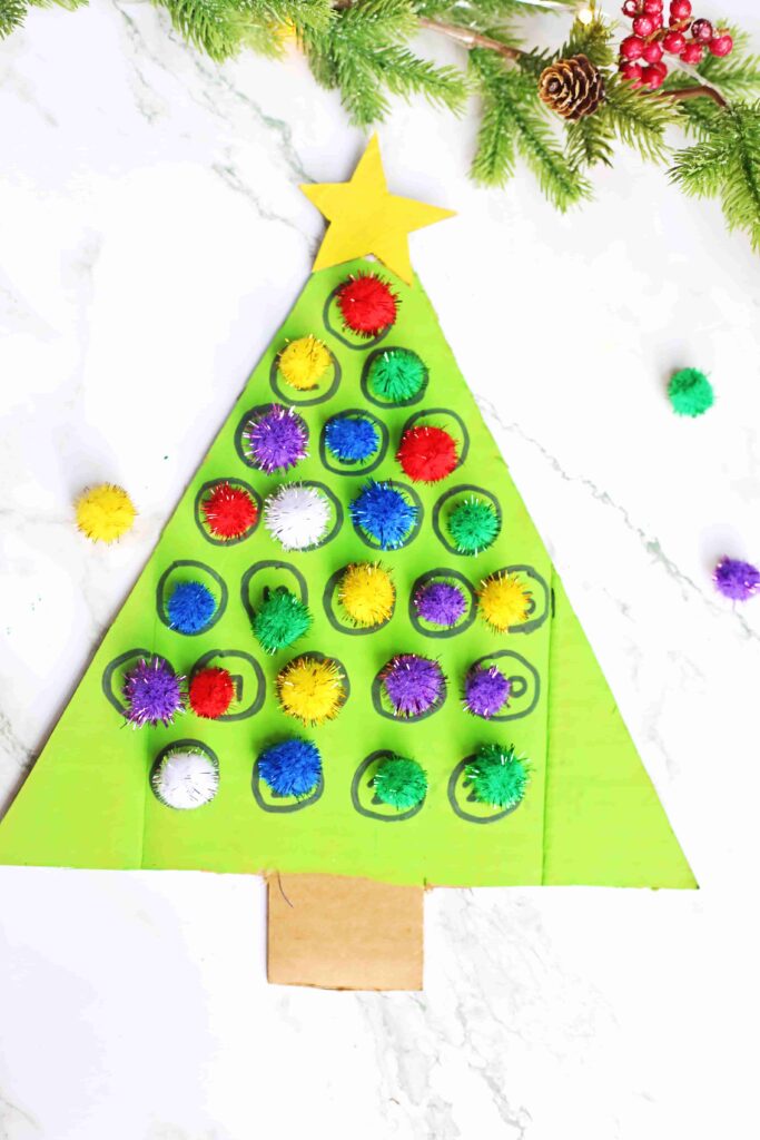 Christmas Tree Countdown Craft - Cultivating Brilliant Minds cardboard painted to look like a christmas tree with numbers on it. Pom poms are glued over some of the numbers