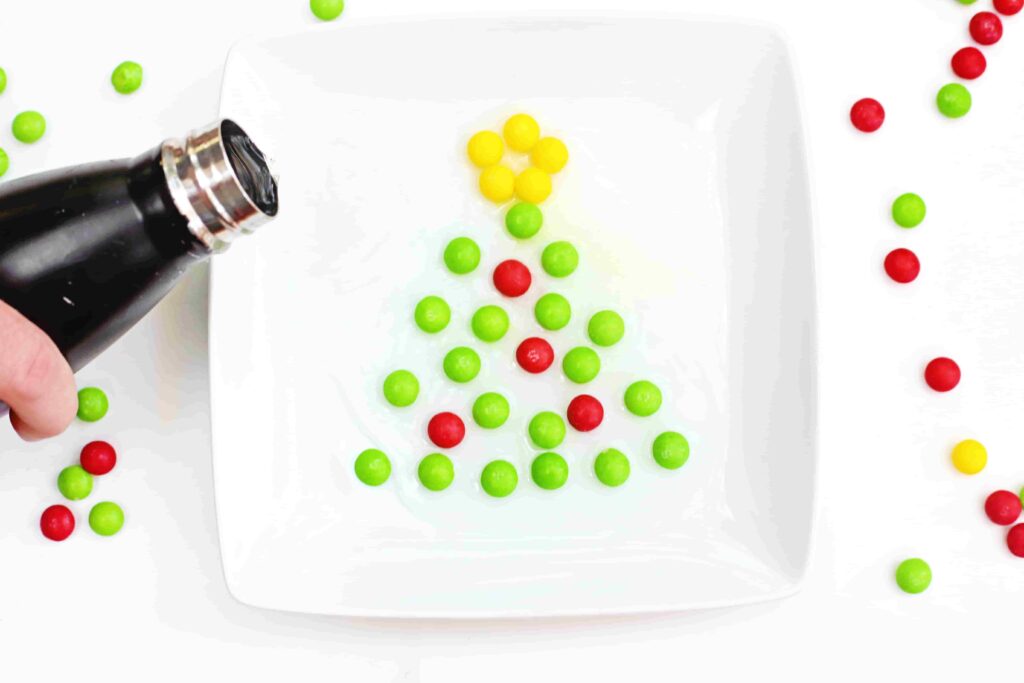 Christmas Tree Skittles Experiment - Cultivating Brilliant Minds pouring water on skittles organized to look like a christmas tree